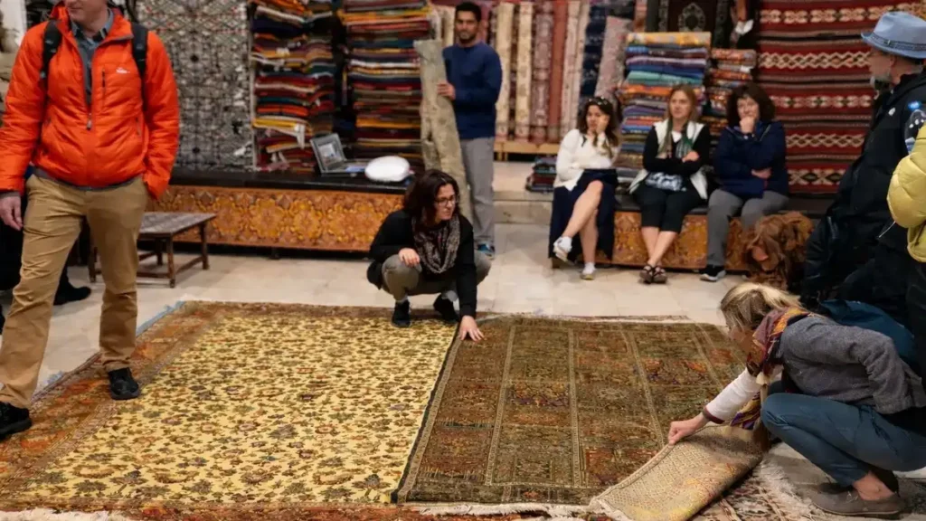Tourists inspecting Moroccan rugs inside a Marrakech rug shop