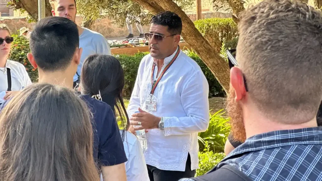 Official Moroccan tour guide explaining local tipping customs to travelers during a guided tour in Morocco