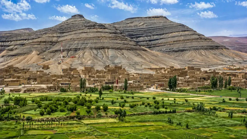 Imilchil Morocco panoramic view of mountain village, green farmland valley, adobe homes, and layered Atlas Mountains landscape near the marriage festival region