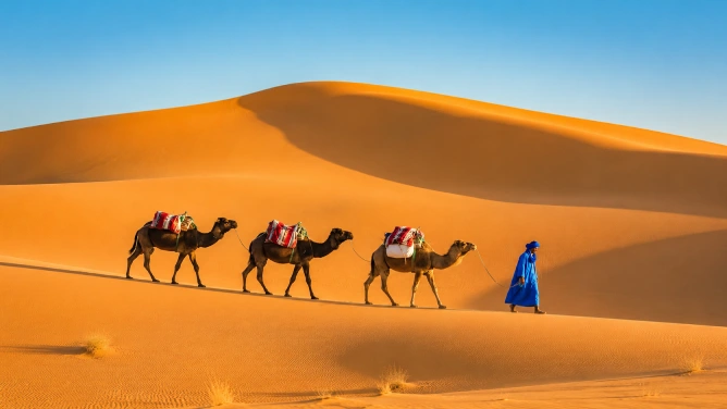 Camel caravan crossing the golden dunes of Merzouga Sahara Desert at sunset, one of the most iconic experiences in a Morocco travel guide
