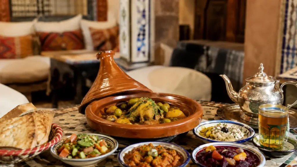 Traditional Moroccan food with tajine, bread, salads, and mint tea served in a local restaurant