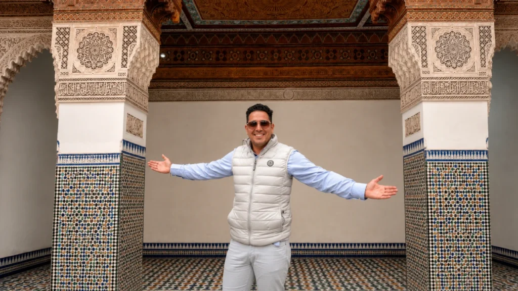 Kamal Official Moroccan Tour Guide Kamal official Moroccan tour guide standing in a traditional Moroccan courtyard with zellige tilework and carved architecture