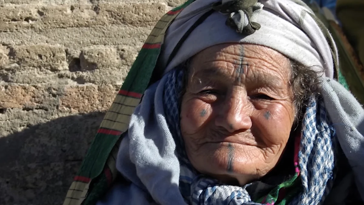 Woman wearing layered headscarves with visible forehead, cheek and chin tattoos