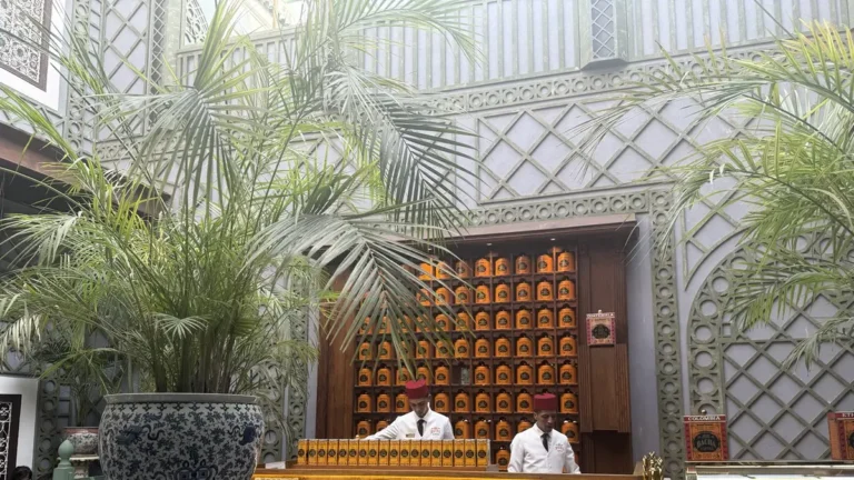 Bacha Coffee Marrakech counter with orange coffee tins, palm plants and decorative walls
