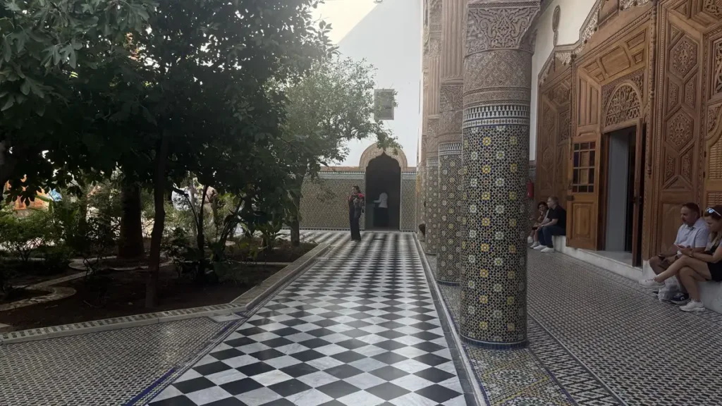 Dar El Bacha courtyard with zellige columns, carved wooden doors and a black-and-white tiled walkway