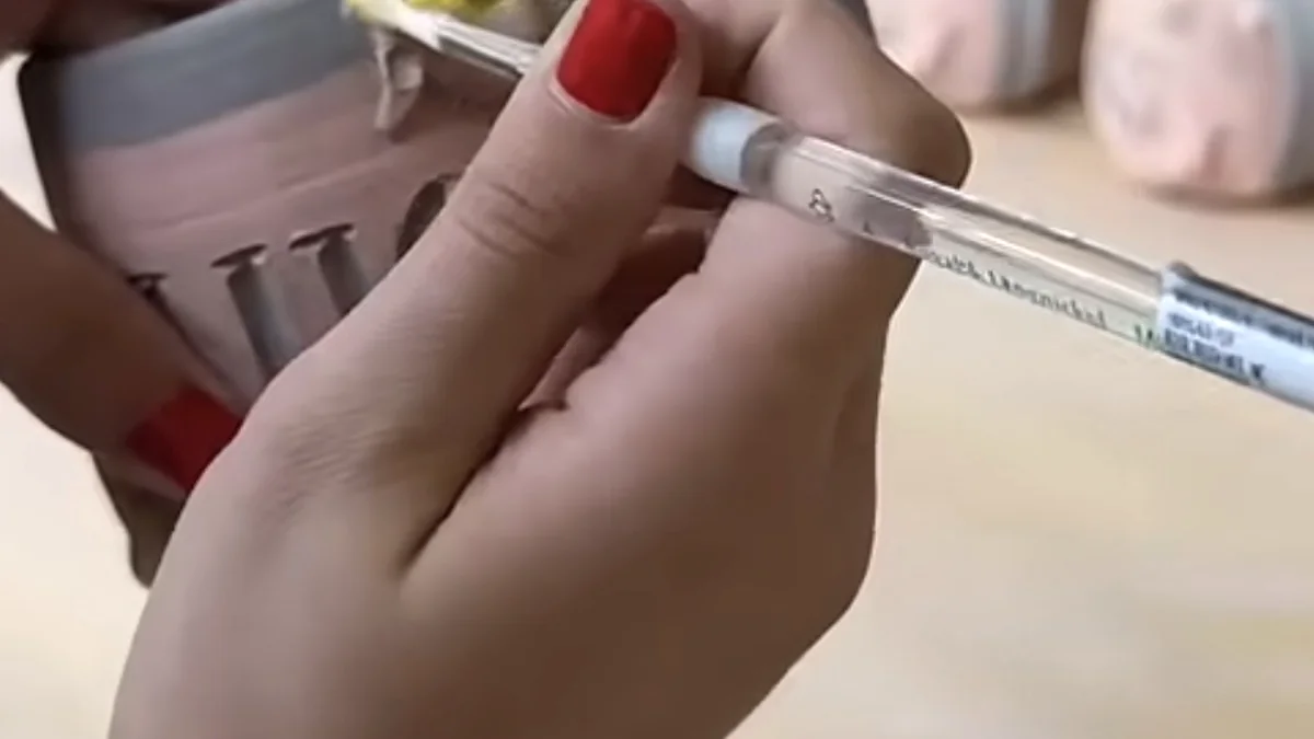 Hands using a paintbrush to decorate a ceramic mug
