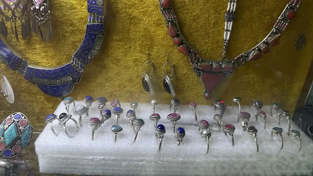 Rings with colorful settings displayed beneath necklaces in Marrakech