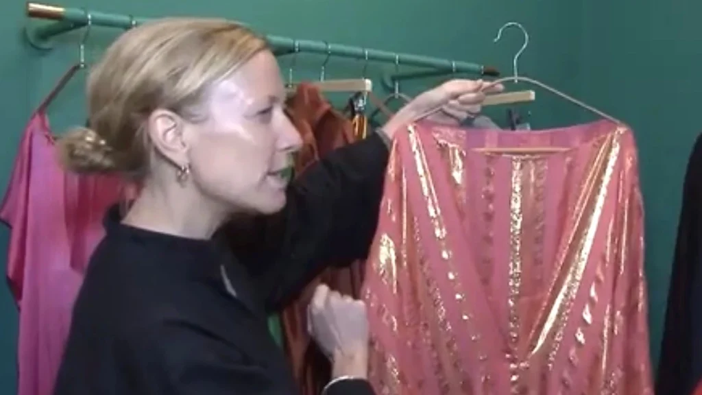 Shopper examining a pink kaftan with gold-colored decoration in a boutique