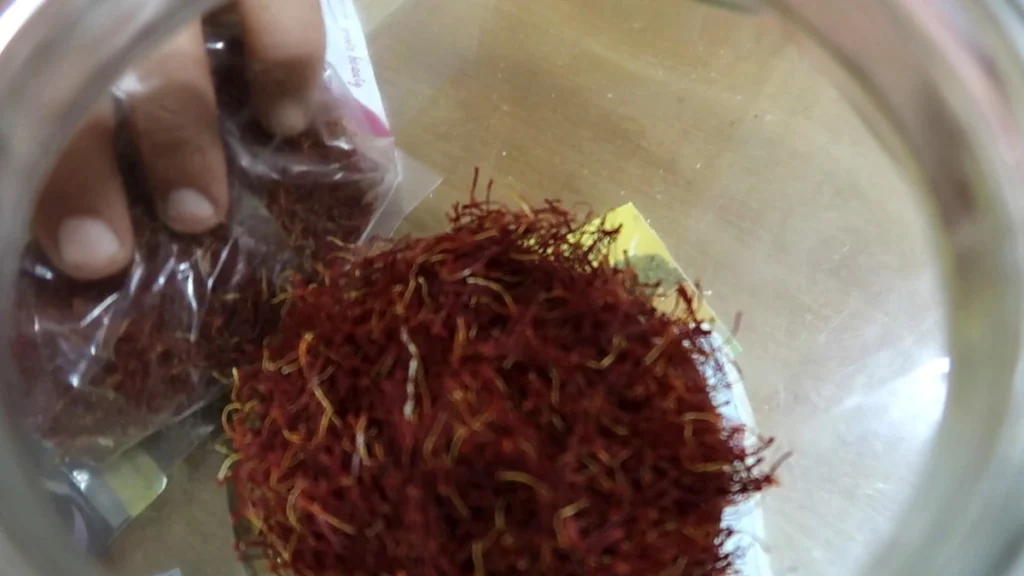 Seller showing red spice threads in a metal tray