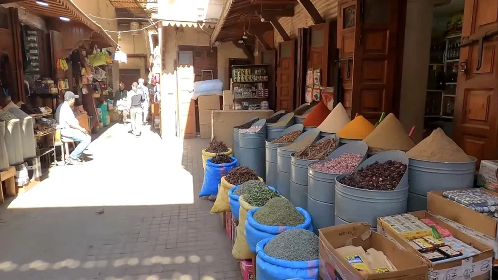 Spice and dried herb displays lining a Marrakech market lane